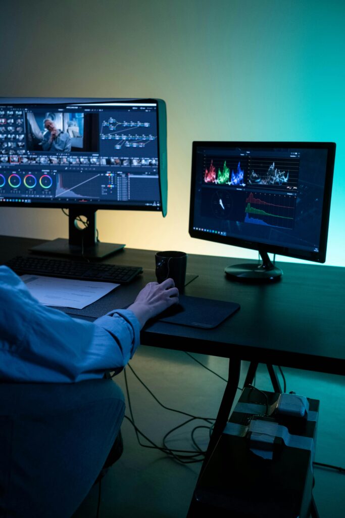 pexels-photo-8100060-8100060 A video editor works on dual monitors in a modern setup, focusing on color grading and editing visuals.